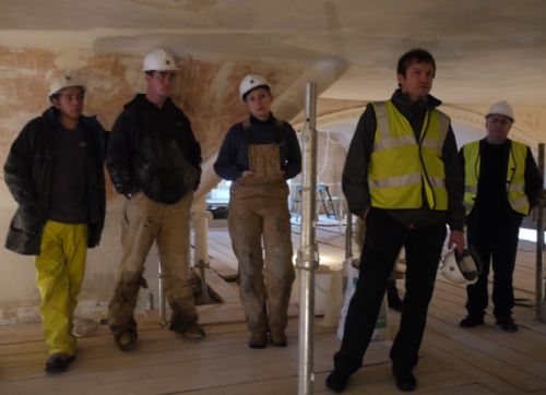 Denis Forrest advises from the back (far right) during a discussion on plastering